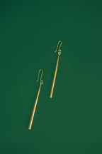 gold drop earrings on a green background