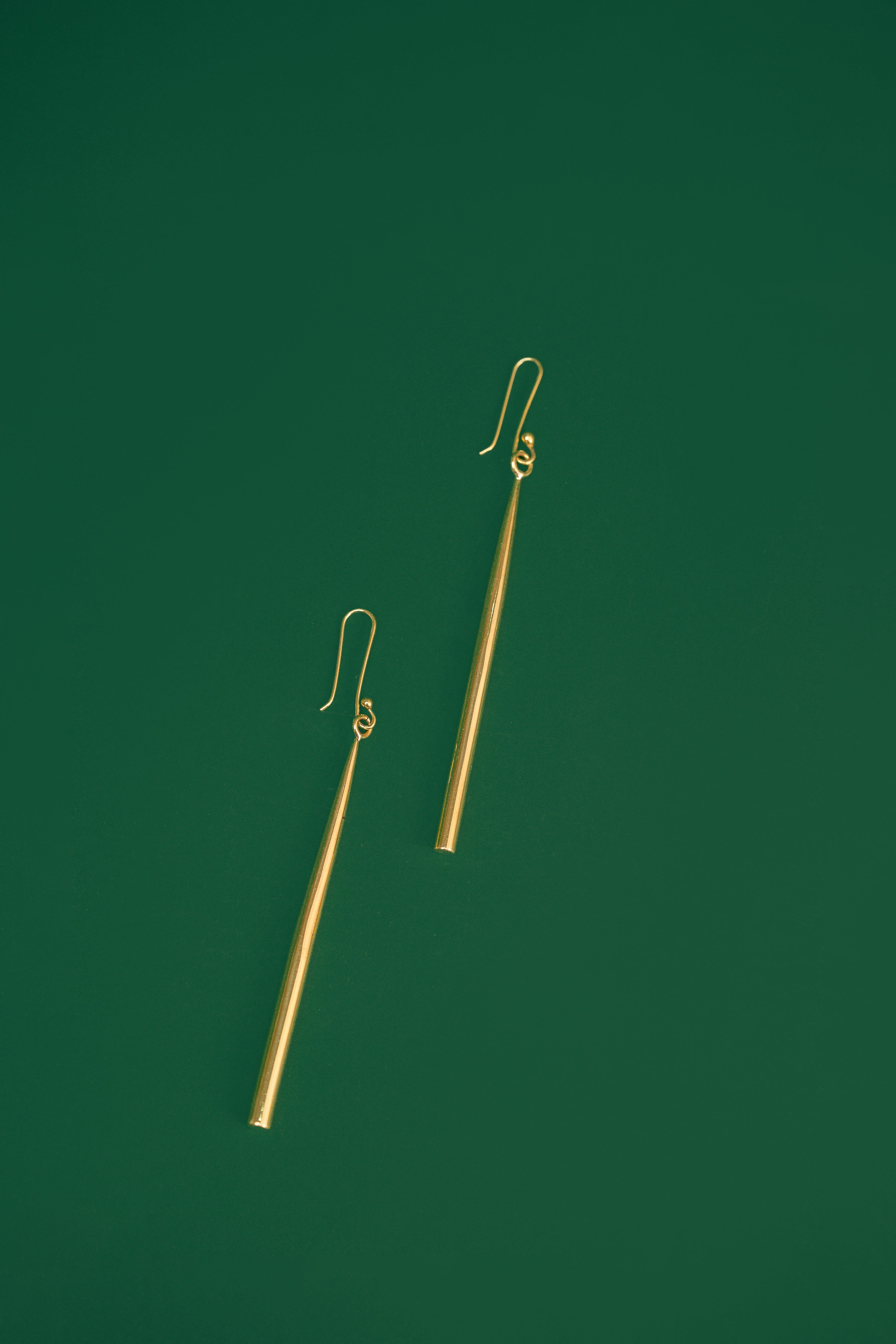 gold drop earrings on a green background