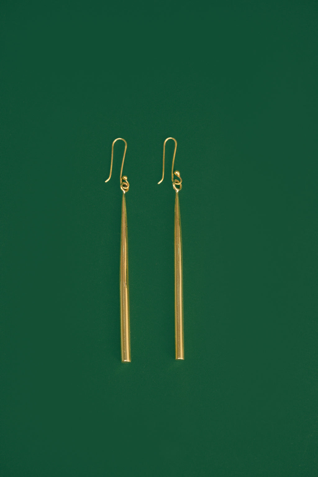 gold drop earrings on a green background