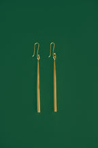 gold drop earrings on a green background