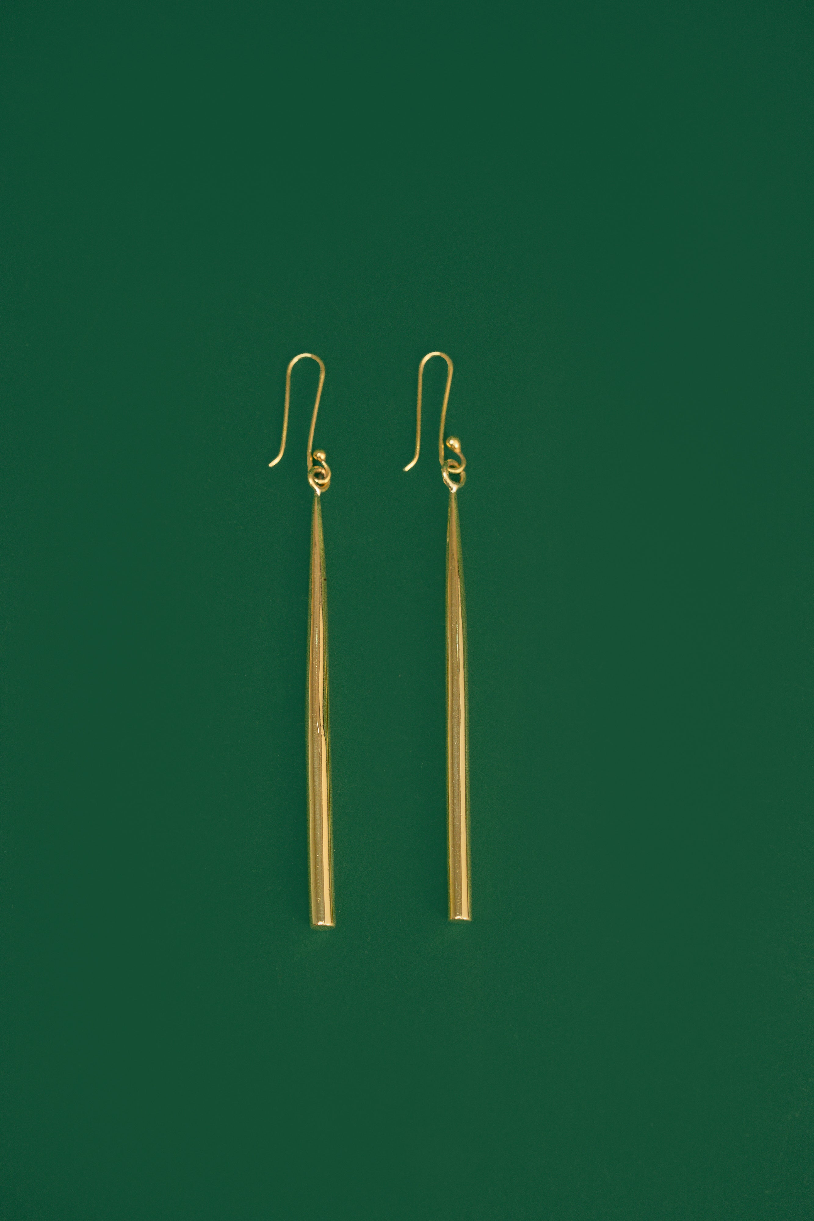 gold drop earrings on a green background