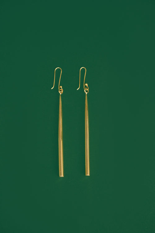 gold drop earrings on a green background