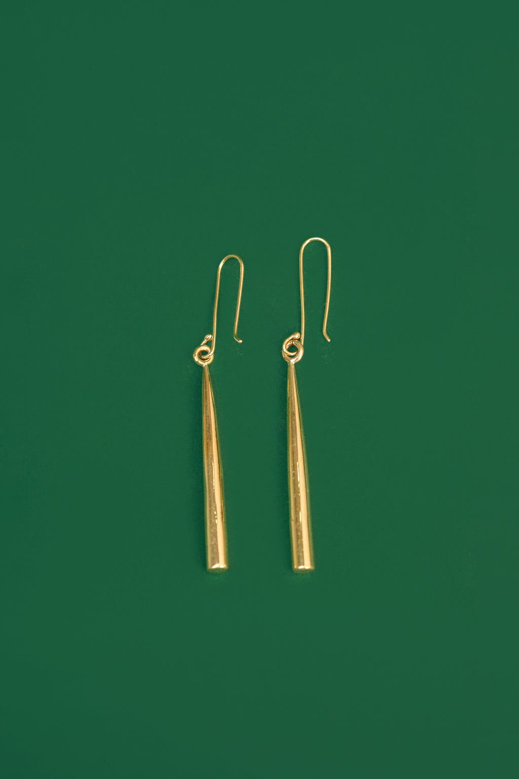 gold drop earrings on a green background