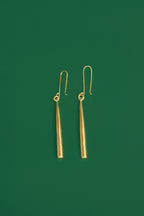 gold drop earrings on a green background