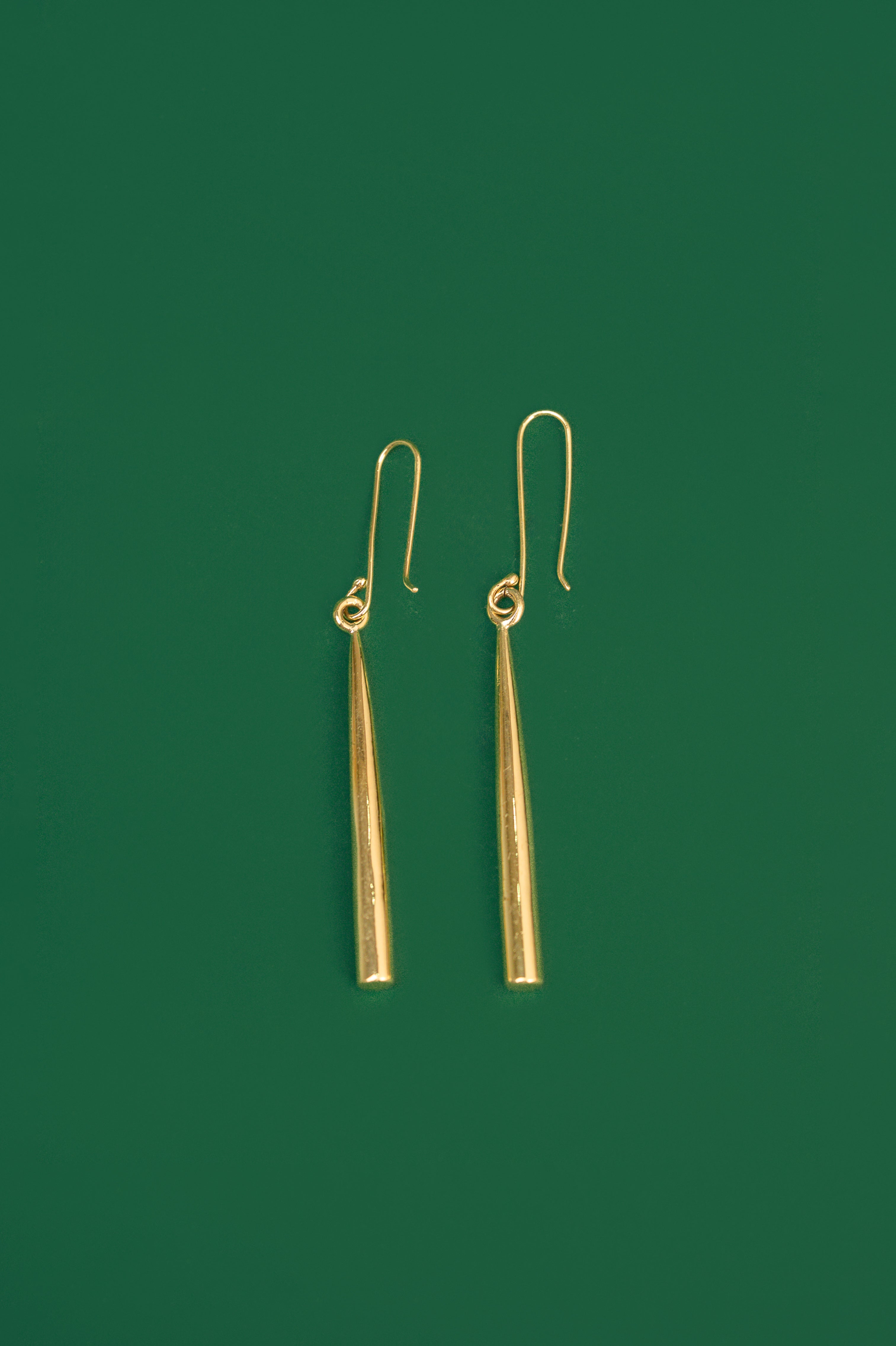 gold drop earrings on a green background