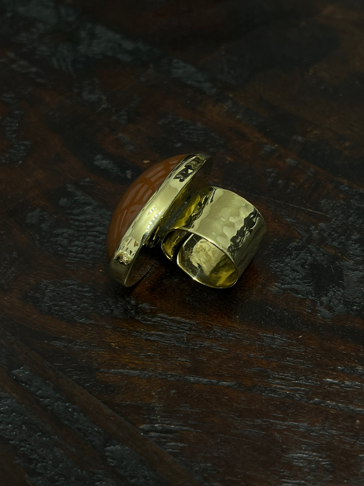 An oval shaped brown gemstone gold ring on a dark wooden surface