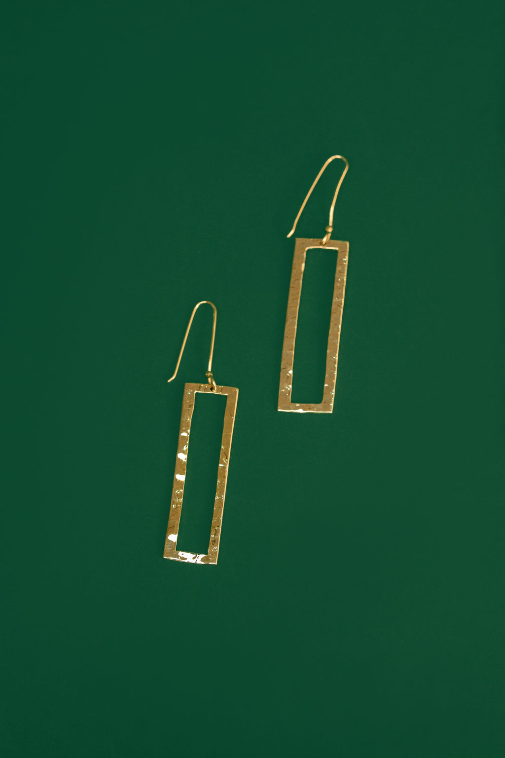 Gold rectangular earrings on a green background