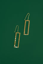 Gold rectangular earrings on a green background