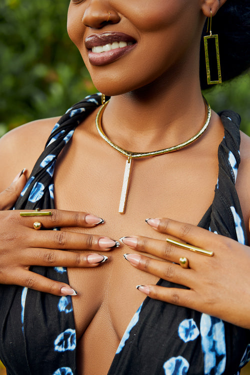 model wearing rectangular bar earrings, a bar pendant choker, and bar shaped rings