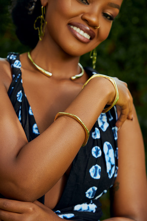 Close-up of a model wearing two gold hexagonal shaped bangle bracelets 