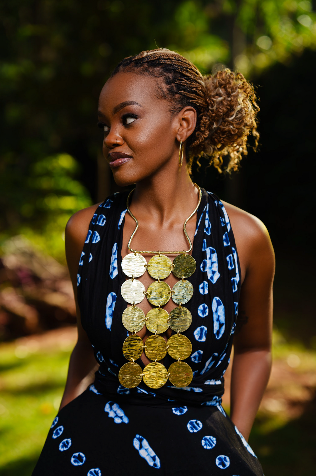 Model wearing a gold statement bib style neckpiece with connected circular disc pendants 