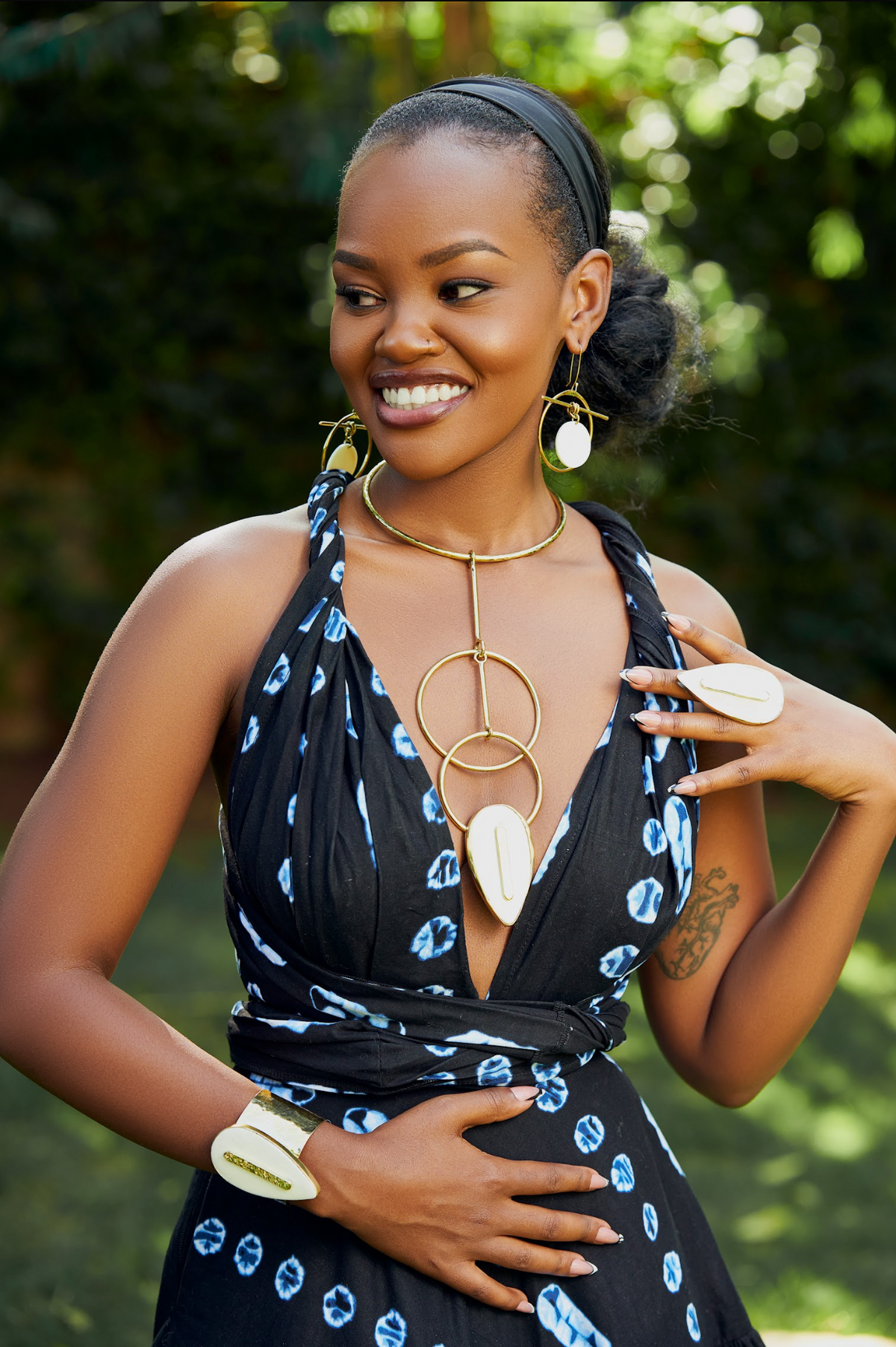 Model wearing an almond shaped white cow horn statement gold ring, matching cuff bracelet and matching neckpiece