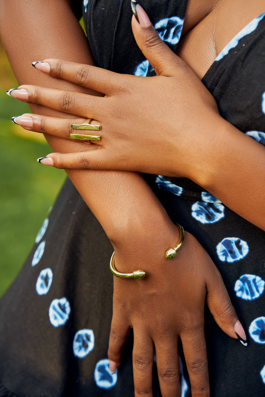 Model wearing a black dress with blue patterns and a gold Double Bar Open Band ring on her finger.