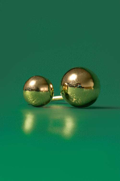A gold double orb design ring on a green background