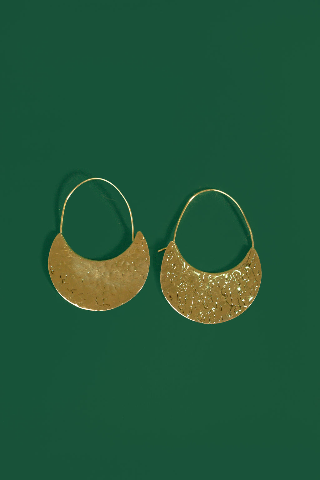 Gold crescent shaped earrings on a green background