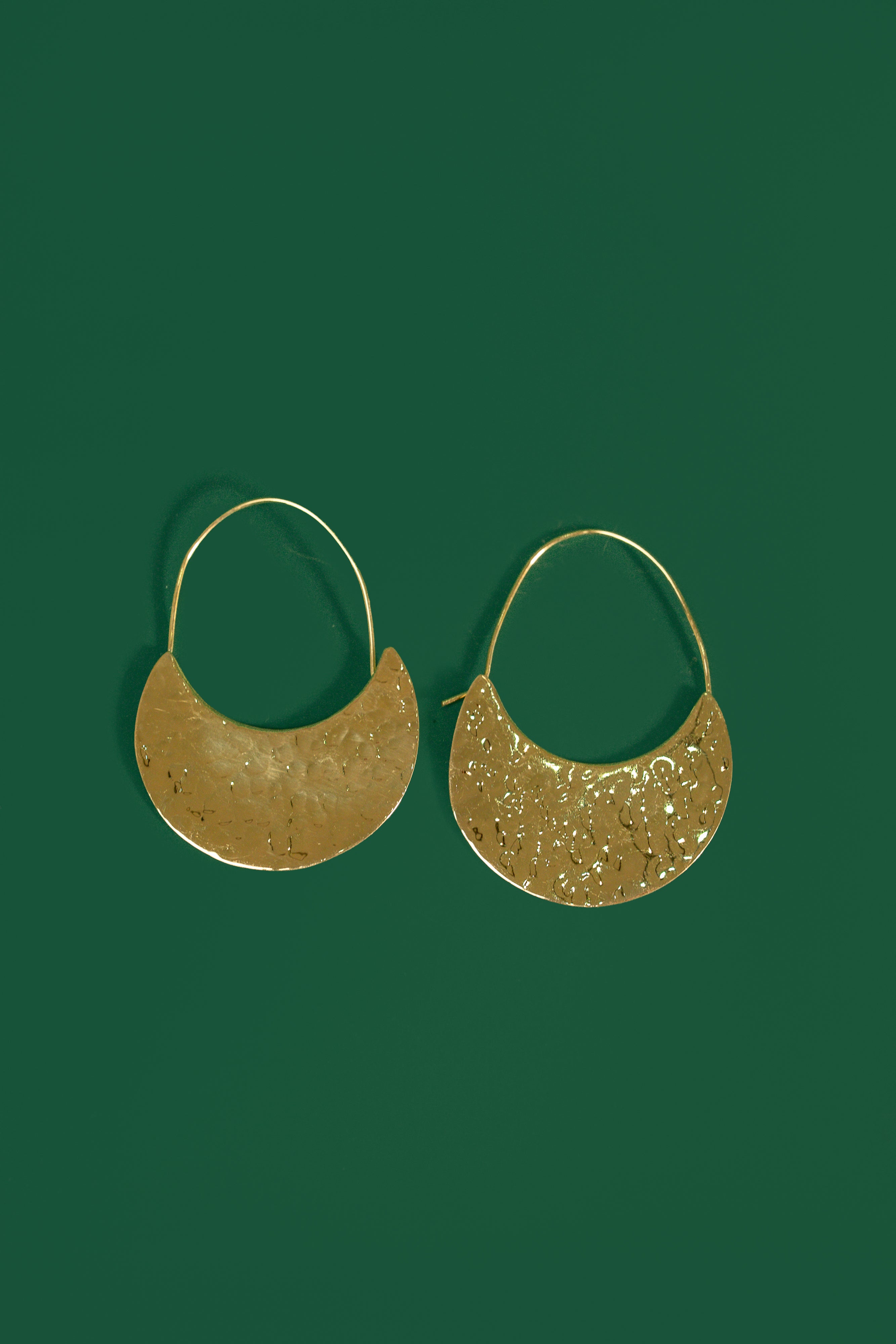 Gold crescent shaped earrings on a green background