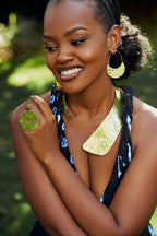 Model wearing gold crescent shaped earrings, circular shaped ring and a statement gold neckpiece