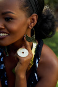 Model wearing gold crescent shaped earrings, circular disc shaped ring and a statement gold neckpiece