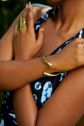 Model wearing a gold twisted bracelet with teardrop-shaped open ends.