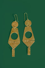 Gold geometric earrings on a green background