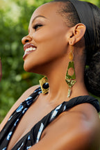 Model wearing gold earrings with geometric shapes cut out pendants