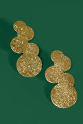A pair of gold cascading circular earrings on a green background