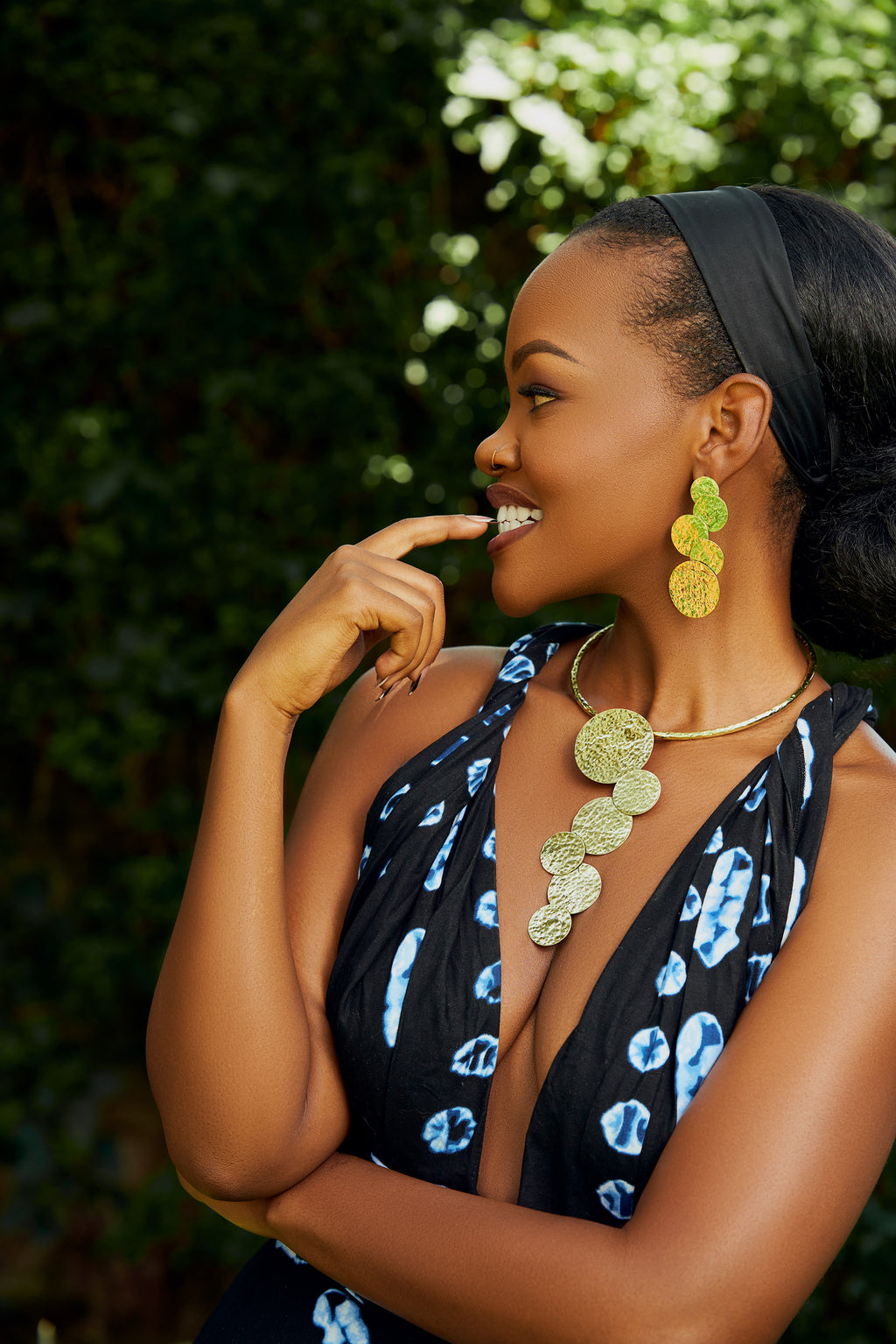 Model wearing a pair of gold cascading circular earrings and a matching choker with gold cascading circles  pendant