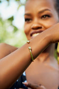 A model wearing a gold bracelet with pointed ends against a blurred background. 