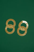 Pair of gold double interlocking hoop earrings on a green background