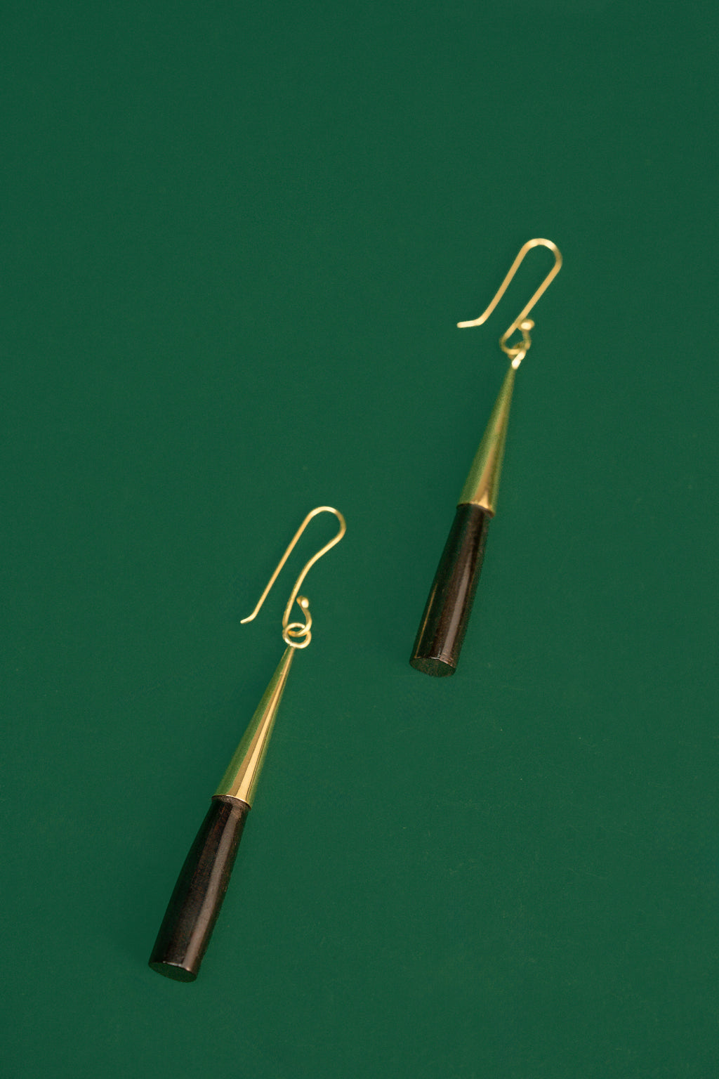 Pair of earrings with black and gold cylindrical design on a green background