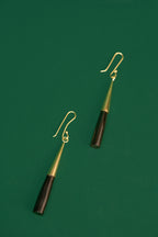 Pair of earrings with black and gold cylindrical design on a green background