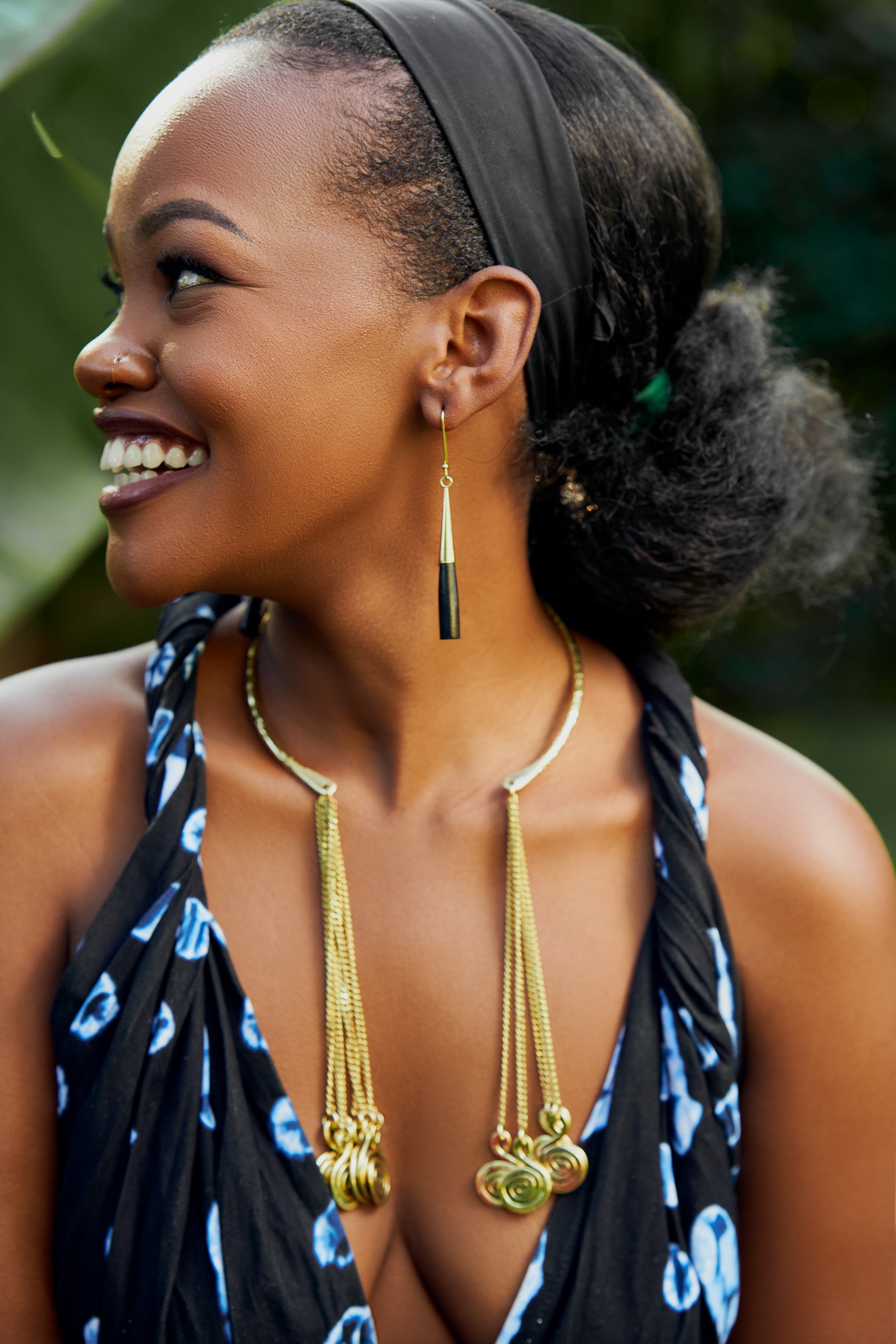 Model wearing black and gold cylindrical bar dangle earrings and a choker with chain spiral ends 