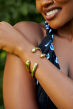 Close-up of a model's arm with gold bracelets with tear drop ends