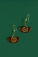 A pair of spiral drop earrings with gold-toned wire spirals and brown semicircular discs, shown on a solid dark green background.