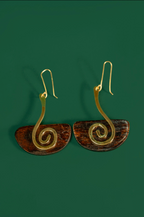 A pair of spiral drop earrings with gold-toned wire spirals and brown semicircular discs, shown on a solid dark green background.