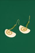 A pair of spiral drop earrings with gold-toned wire spirals and white semicircular discs, shown on a solid dark green background.