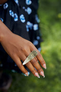 model wearing a gold hammered ring with one tapered end, and the other end is rounded. 