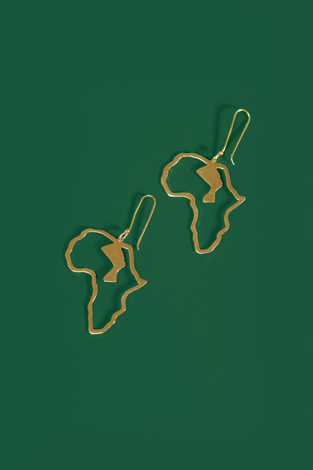 Gold Africa shaped earrings on a green background