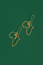 Gold Africa shaped earrings on a green background