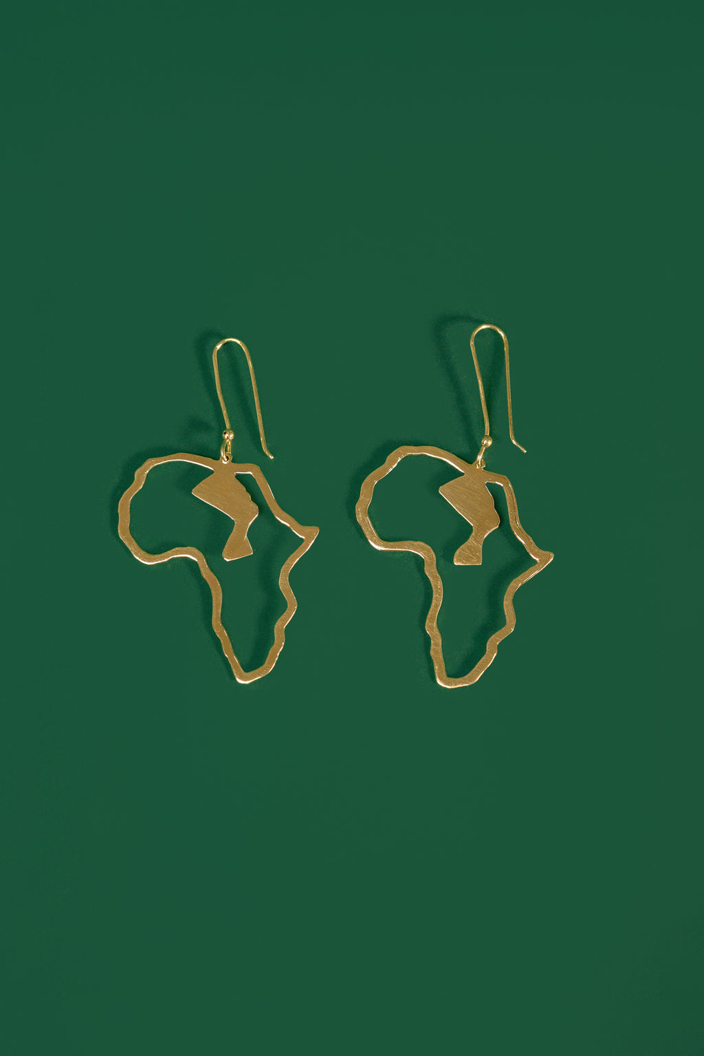 Gold Africa shaped earrings on a green background
