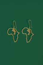 Gold Africa shaped earrings on a green background