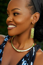 Model wearing gold rectangular earrings and a gold choker 