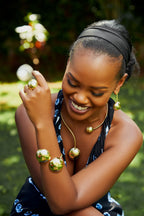 Model wearing gold spherical drop earrings and a neckpiece and bracelet with spherical ends