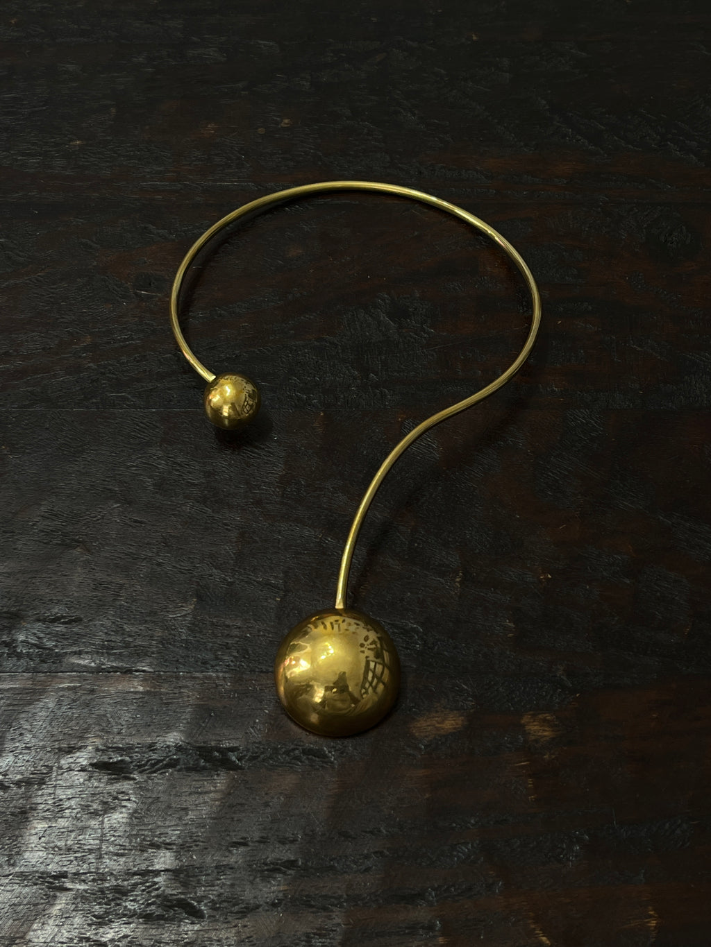 Gold necklace with spherical ends on a dark wooden surface