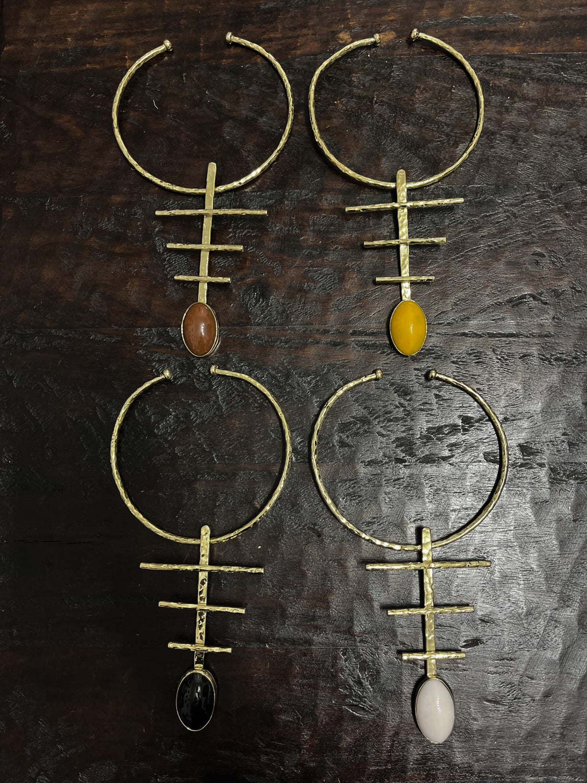 Set of unique neckpieces with different colored stone pendants on a dark wooden surface