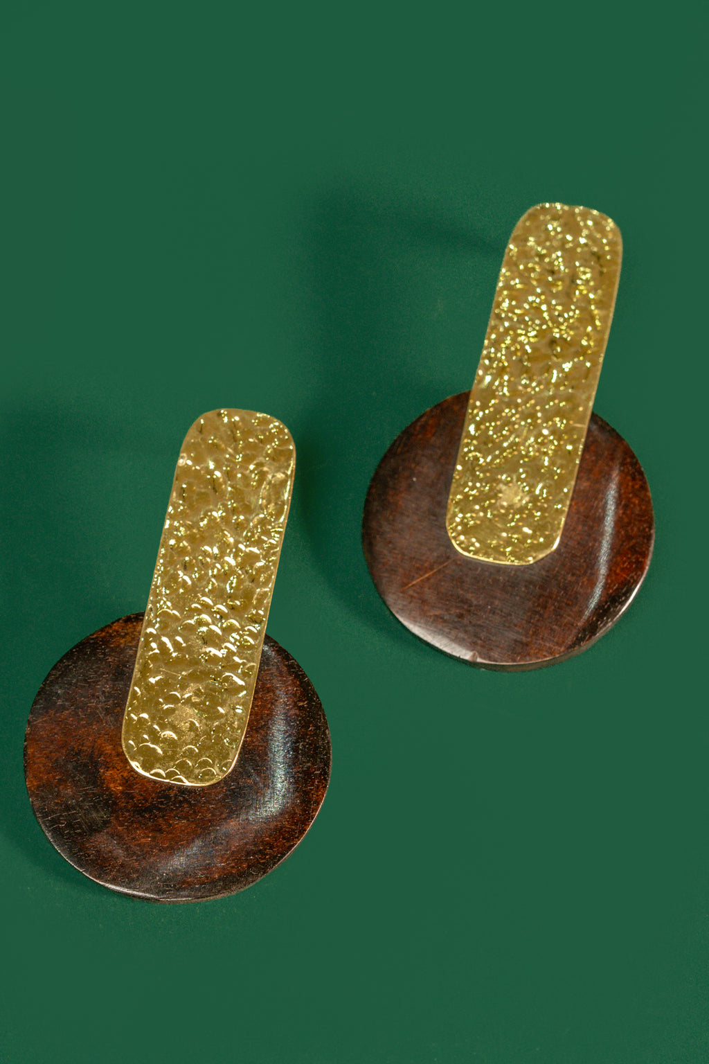 Pair of gold and brown earrings on a green background