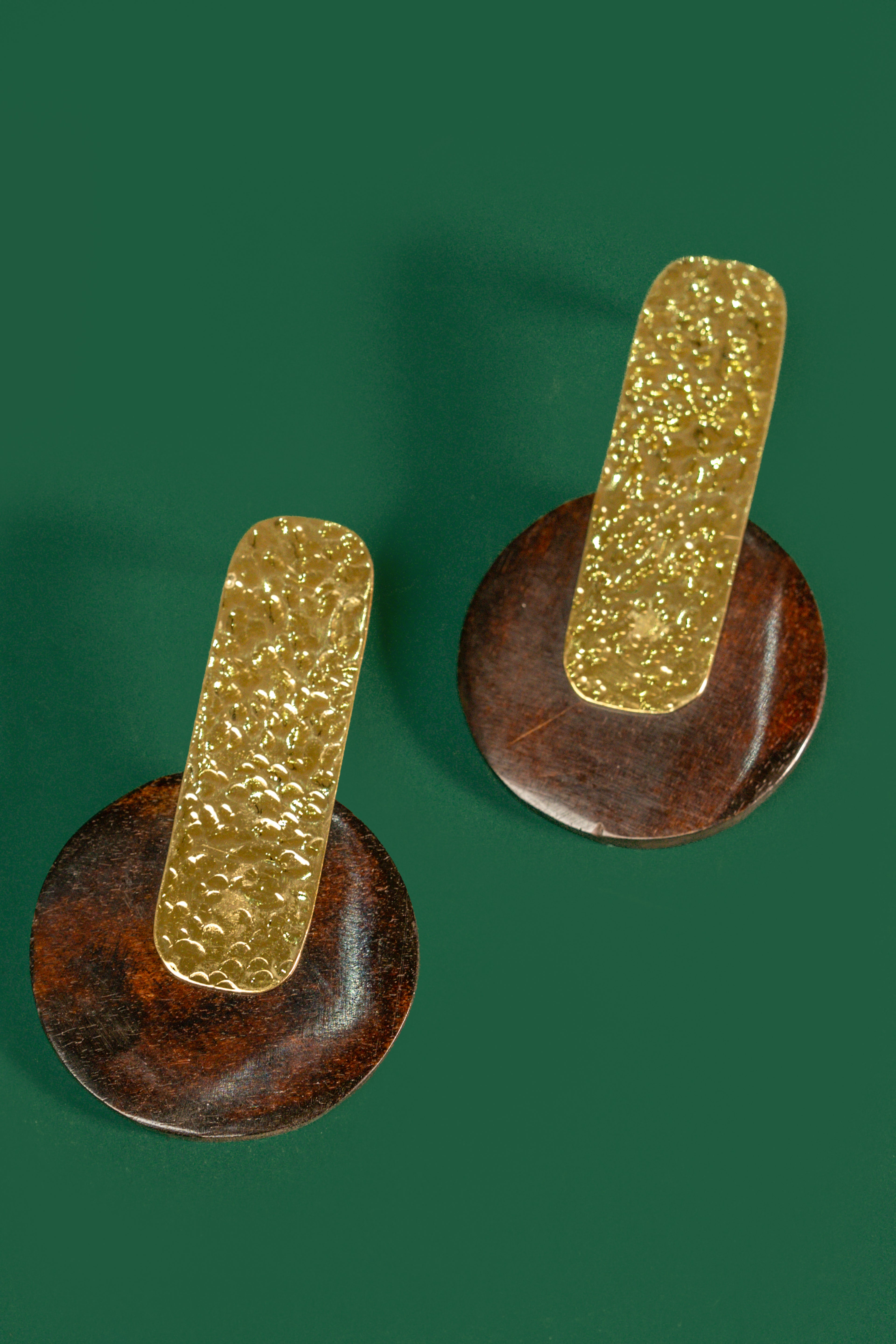Pair of gold and brown earrings on a green background