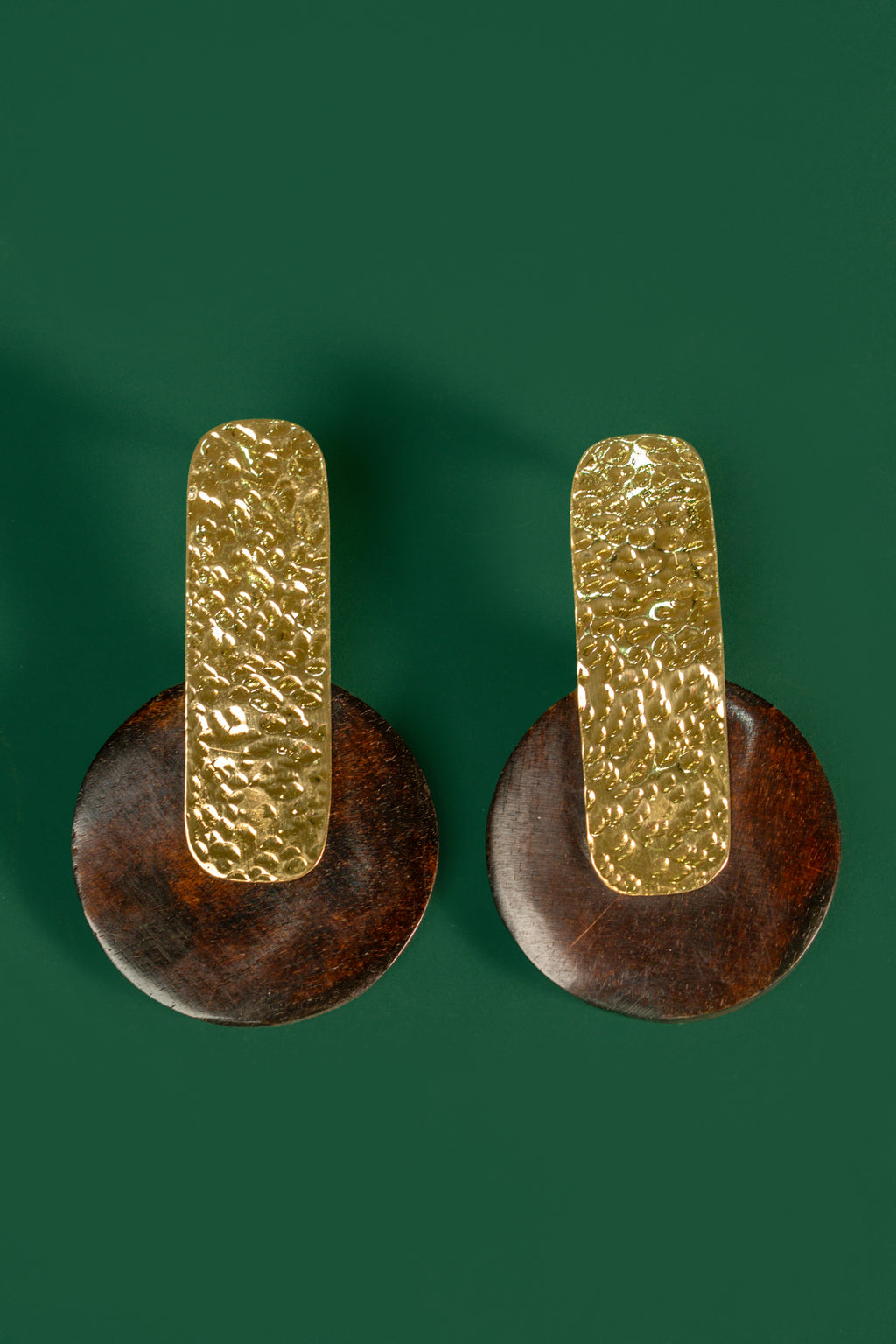 Pair of gold and brown earrings on a green background