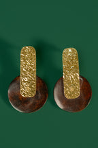 Pair of gold and brown earrings on a green background