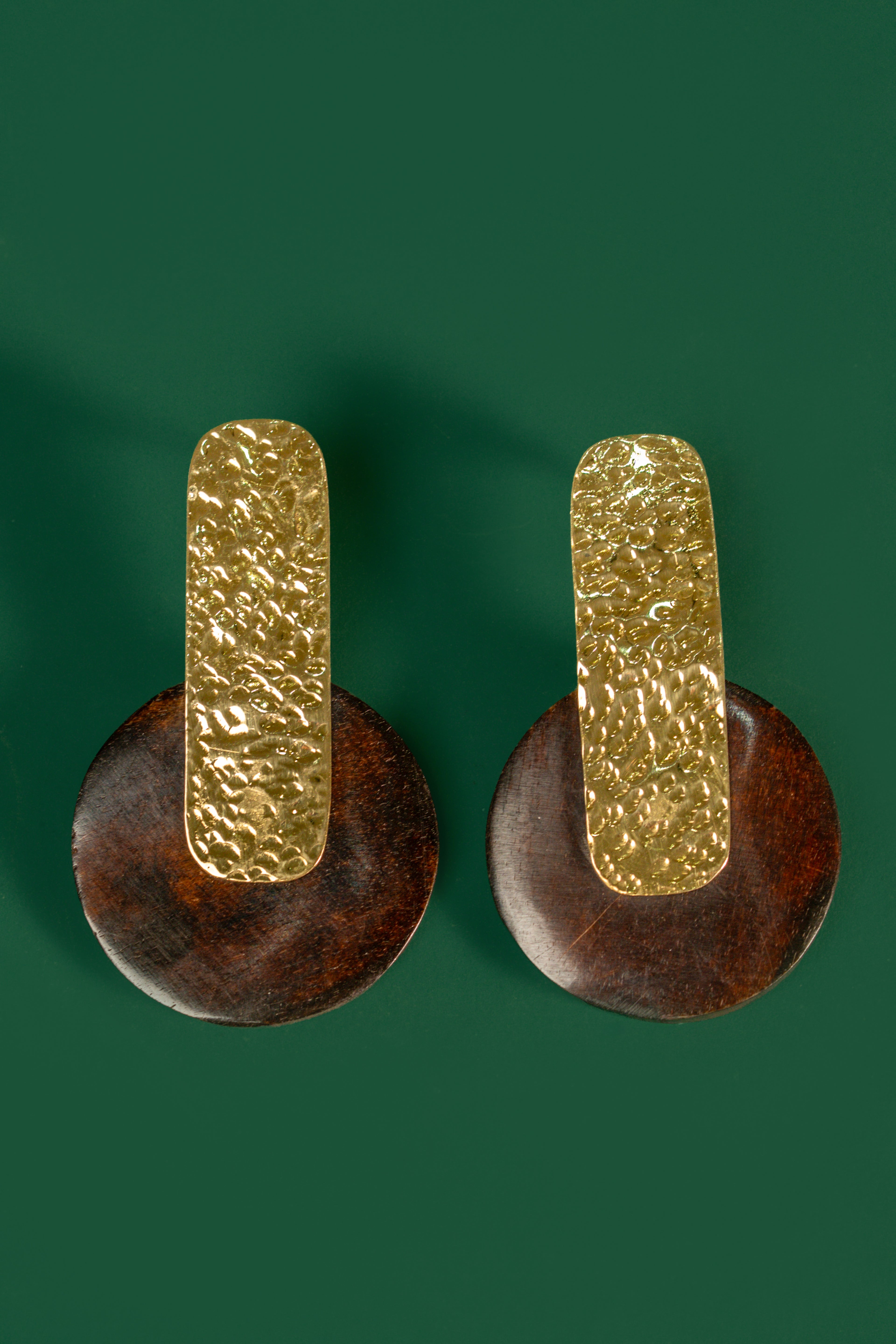 Pair of gold and brown earrings on a green background